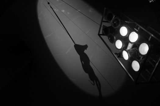 Black and white image of Focus on light equipment during training of female acrobat