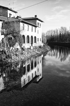 Black and White image of small pond with building reflection on water