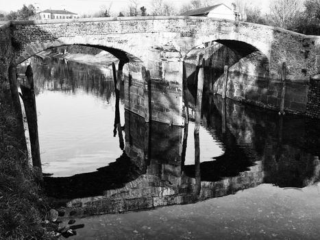 Black and White image of old bridge reflection on water