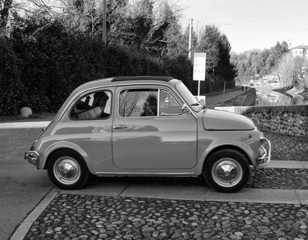 Black and White image of small car on parking place