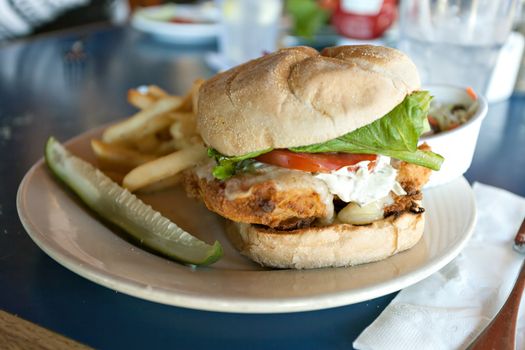 Fried fish sandwich with tartar sauce and french fries.