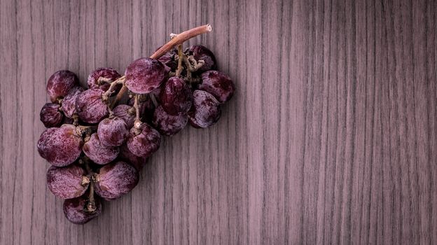 A bunch of overripe red grapes on wood