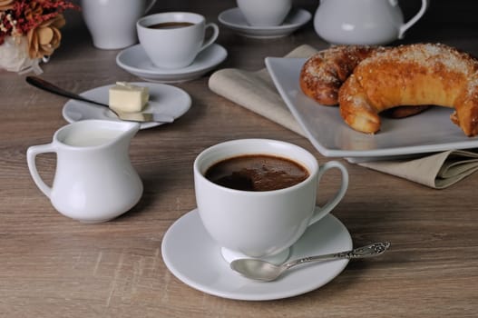 Cup of coffee with croissants, butter and milk on the table