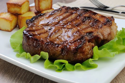 A piece of juicy pork steak grilled with roasted potatoes