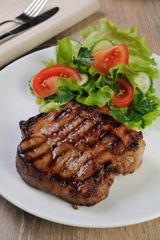 A piece of juicy pork steak grilled with a salad