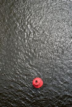 Red round buoy on the water surface. View from above.