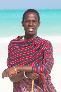 Traditonaly dressed black man on the beach. Maasai warrior on picture perfect tropical sandy beach on Zanzibar, Tanzania, East Africa.