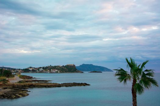Nice Greek rocky beach with palm trees under a perfectly shaped cloudscape