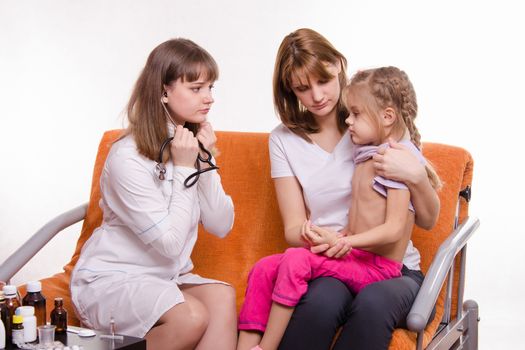Doctor pediatrician examines a sick child at home in the presence of my mother
