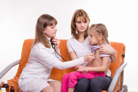 Doctor pediatrician examines a sick child at home in the presence of my mother