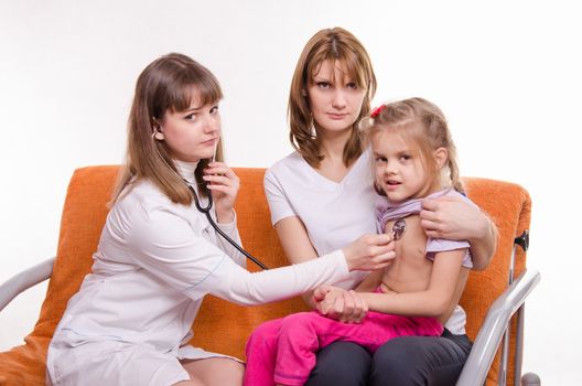 Doctor pediatrician examines a sick child at home in the presence of my mother