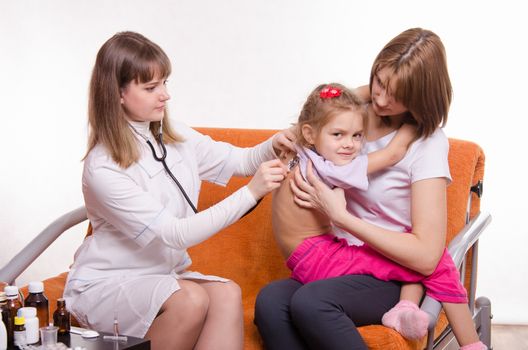Doctor pediatrician examines a sick child at home in the presence of my mother