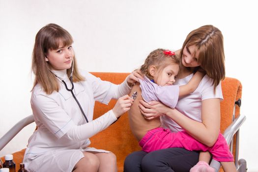 Doctor pediatrician examines a sick child at home in the presence of my mother