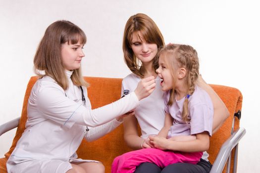 Doctor pediatrician examines a sick child at home in the presence of my mother