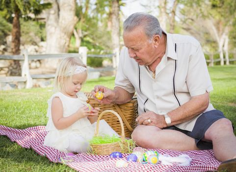 Loving Grandfather and Granddaughter Enjoying Easter Eggs on a Picnic Blanket At Park.