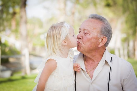 Loving Grandfather and Granddaughter Kissing Outside At The Park.