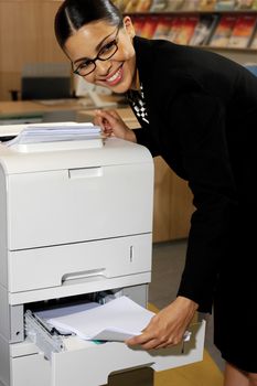 Pretty young businesswoman using Xerox machine at the office 