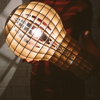 Hanging, wooden light shade lamp with bulb in hands