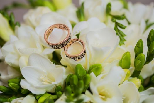 Two wedding rings in infinity sign with bouquet on black background. Love concept.