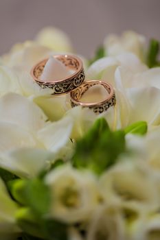 Two wedding rings in infinity sign with bouquet on black background. Love concept.