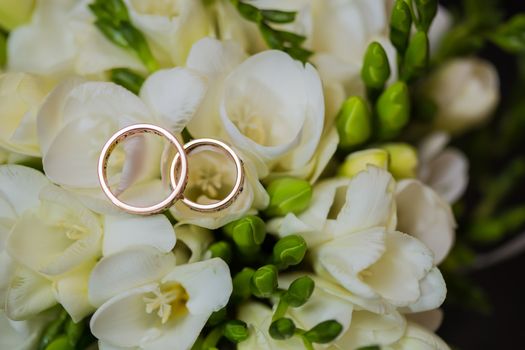 Two wedding rings in infinity sign with bouquet on black background. Love concept.