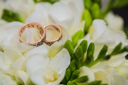 Two wedding rings in infinity sign with bouquet on black background. Love concept.