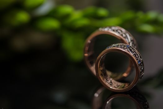 Two wedding rings in infinity sign with bouquet on black background. Love concept.