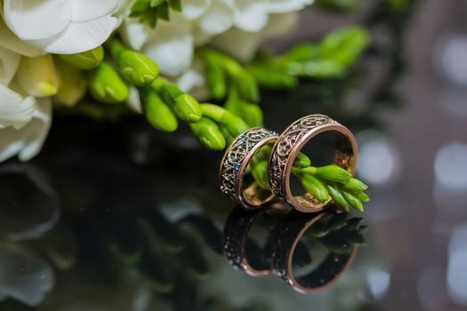 Two wedding rings in infinity sign with bouquet on black background. Love concept.