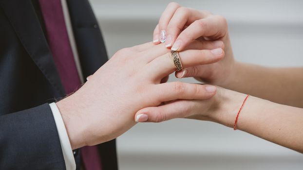 Bride putting a wedding ring on groom&#39;s finger