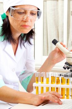 scientist near the microscope enter the data into the computer