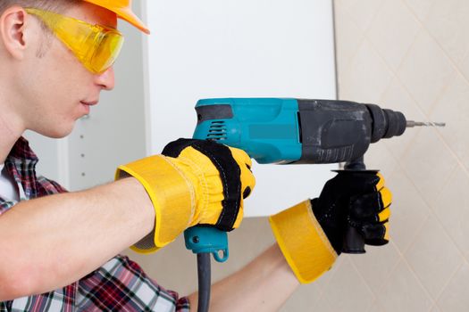 worker in protective gloves and eyeglasses with perforator