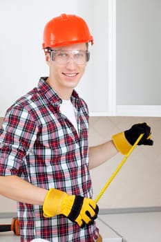 repairman with a tape measure and a red protective helmet