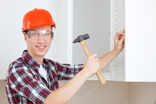 young worker with a hammer drives a nail