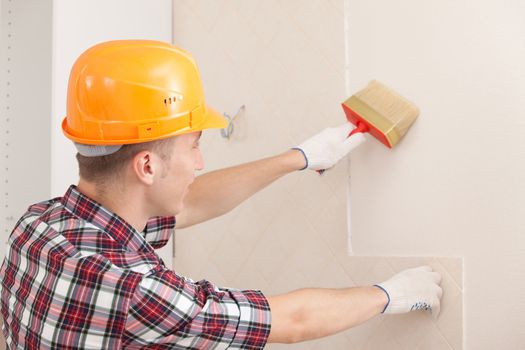 worker with paint brush prepares the wall for wallpapering