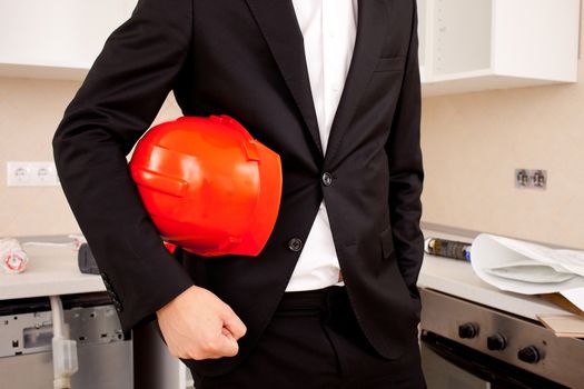 Close-up of businessman holding red helmet on interior background