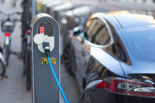 Power supply for electric car charging.  Electric car charging station. Close up of the power supply plugged into an electric car being charged.