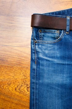Aged jeans with a leather belt on wooden boards. copy space