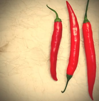 three red hot chili peppers on the paper background. instagram image style