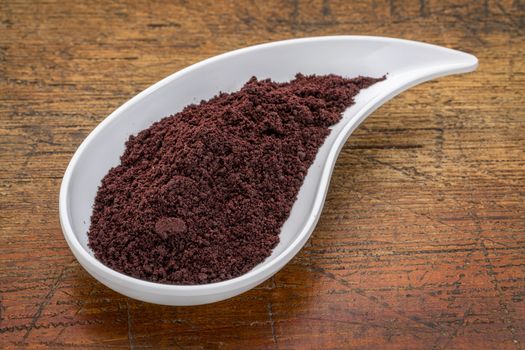 dried acai berry powder in a teardrop shaped bowl against rustic wood