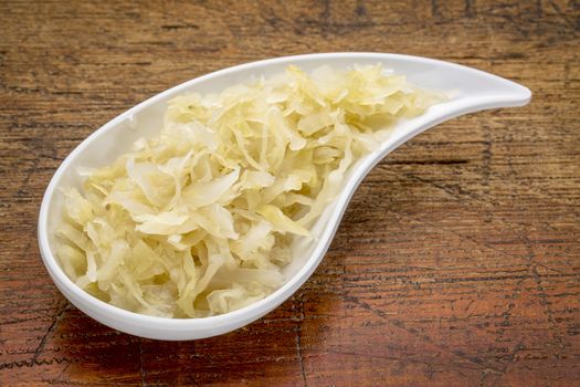 sauerkraut side dish - a white teardrop shaped bowl against rustic wood