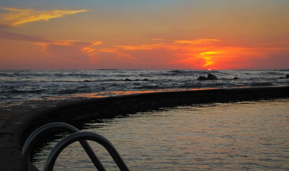 Sun goes down on a beach and salt water pool at a resort in El Salvador, Central America.