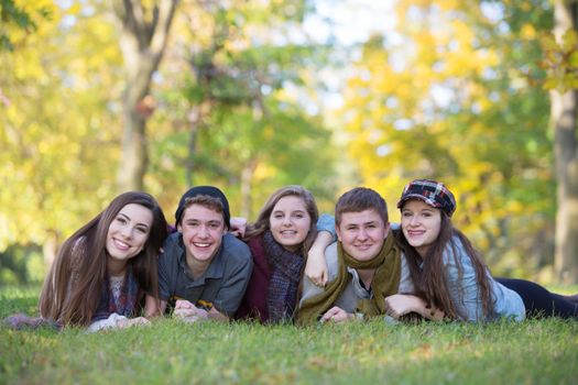 Group of five male and female teens laying down outdoors