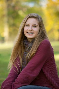 Beautiful teenage girl in red sweater sitting outdoors