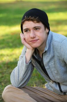 Young white teenager in hat sitting and looking away