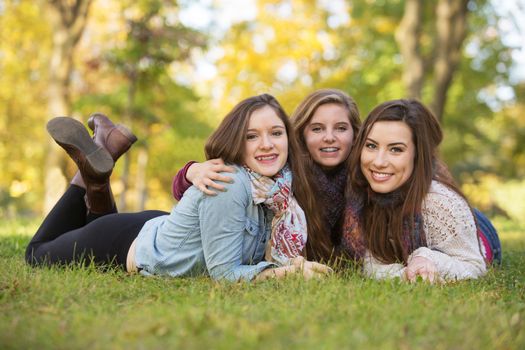 Trio of happy teen girls laying down on grass