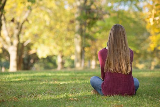 Unidentifiable woman sitting cross legged on grass