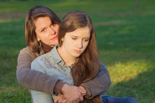 Concerned European mother holding depressed daughter outdoors