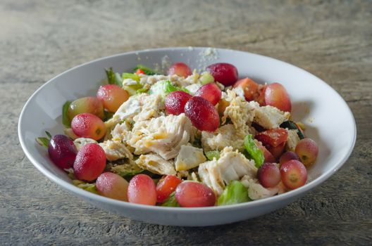 Mix salad with grapes and chicken on white dish