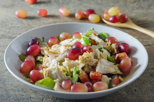 Mix salad with grapes and chicken on white dish