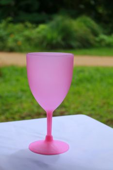 The pink plastic wine cup is on the table.But have nothing in the cup.